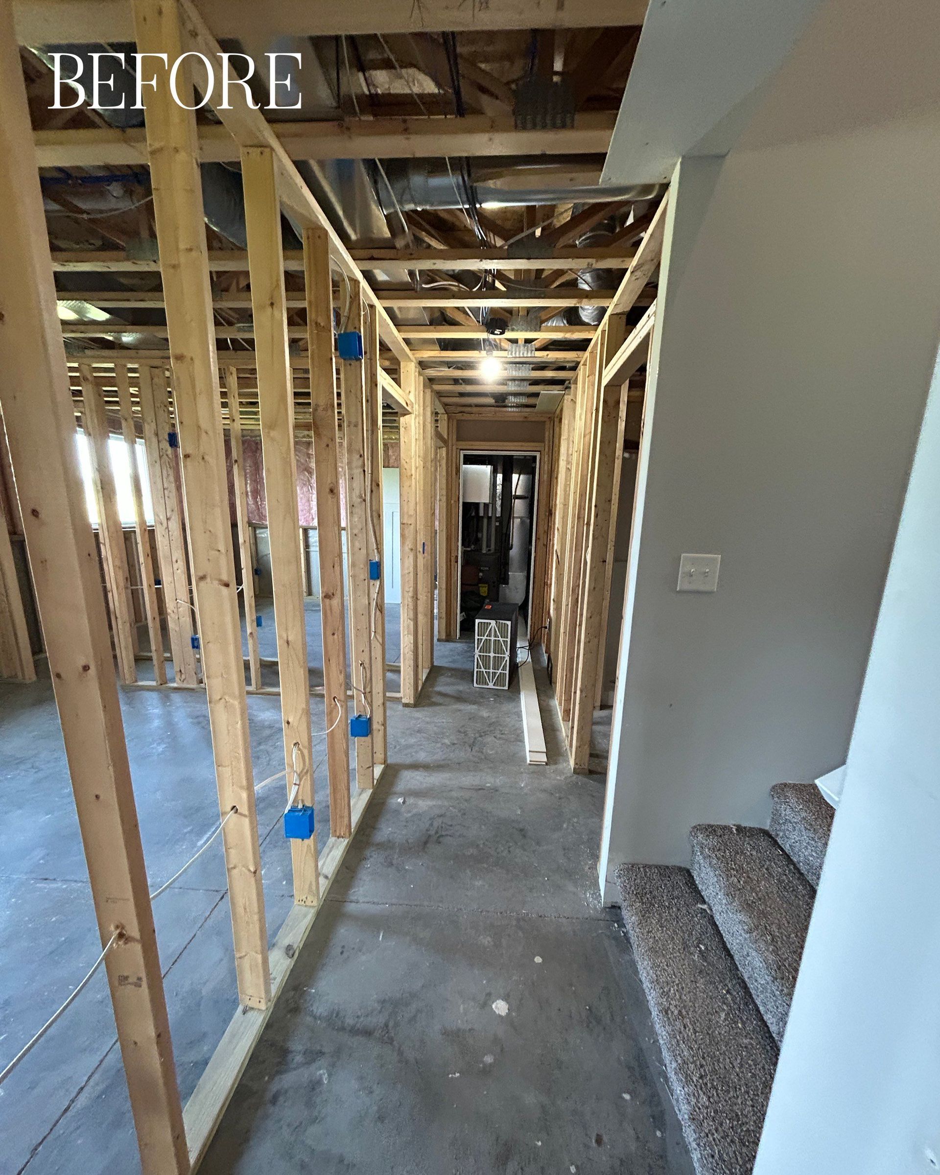Interior hallway under construction; wood framing and concrete floor; stairs visible.
