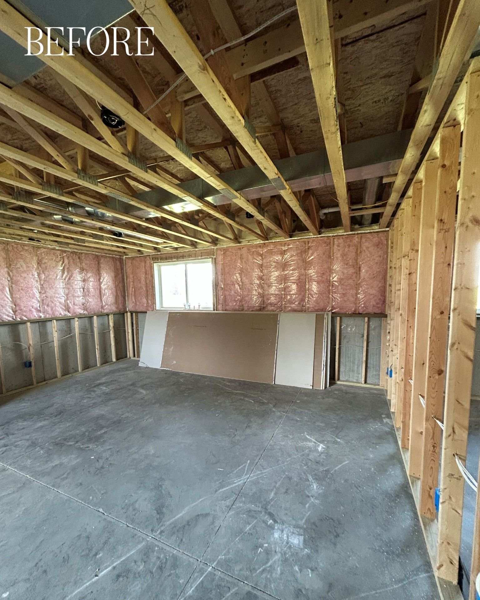 Unfinished room interior with wood framing, insulation, and drywall. 
