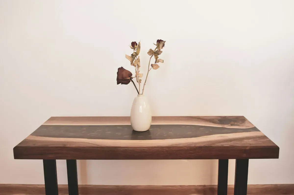 Rustic wood table and bench set in a workshop with shelves and tools in the background