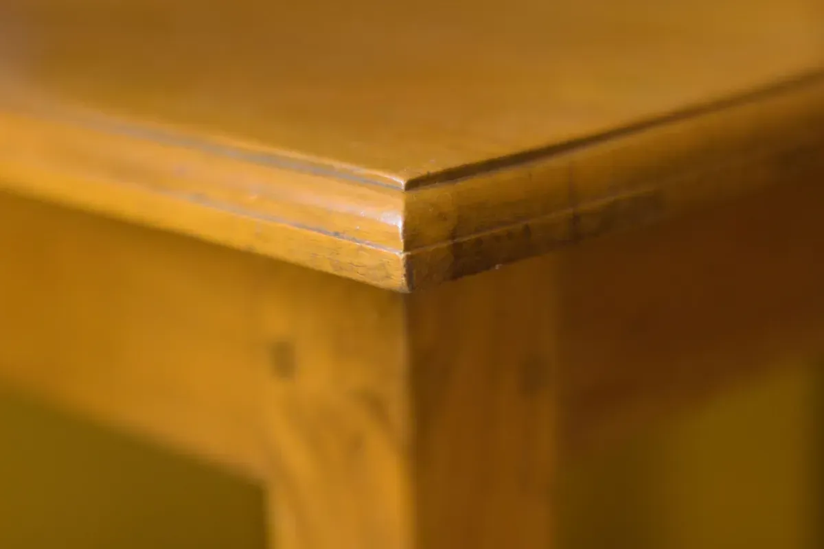 Rustic wood table and bench set in a workshop with shelves and tools in the background