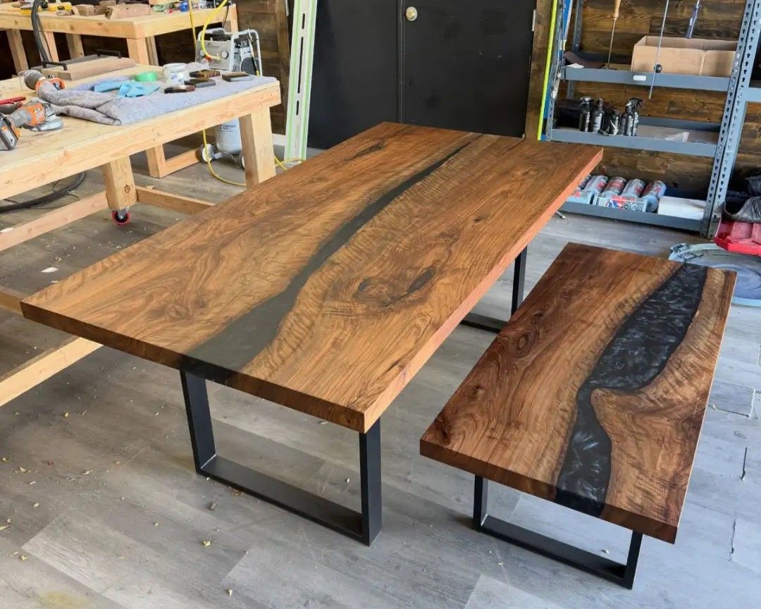 Rustic wood table and bench set in a workshop with shelves and tools in the background