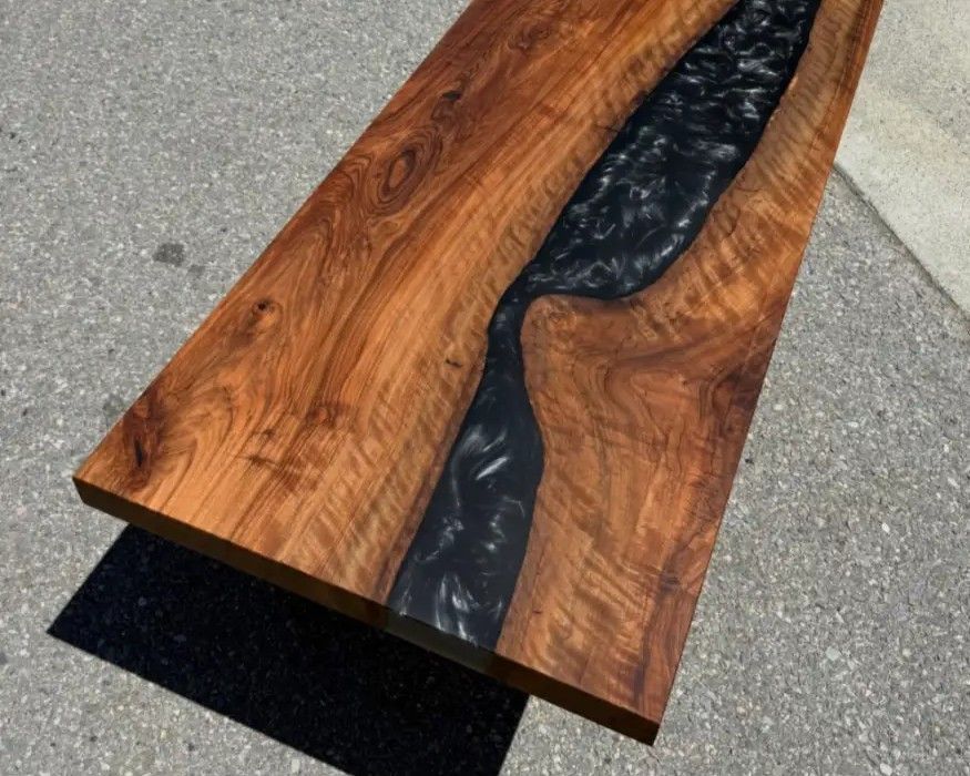 Wooden resin tabletop with a black flowing center, shown outdoors on pavement.