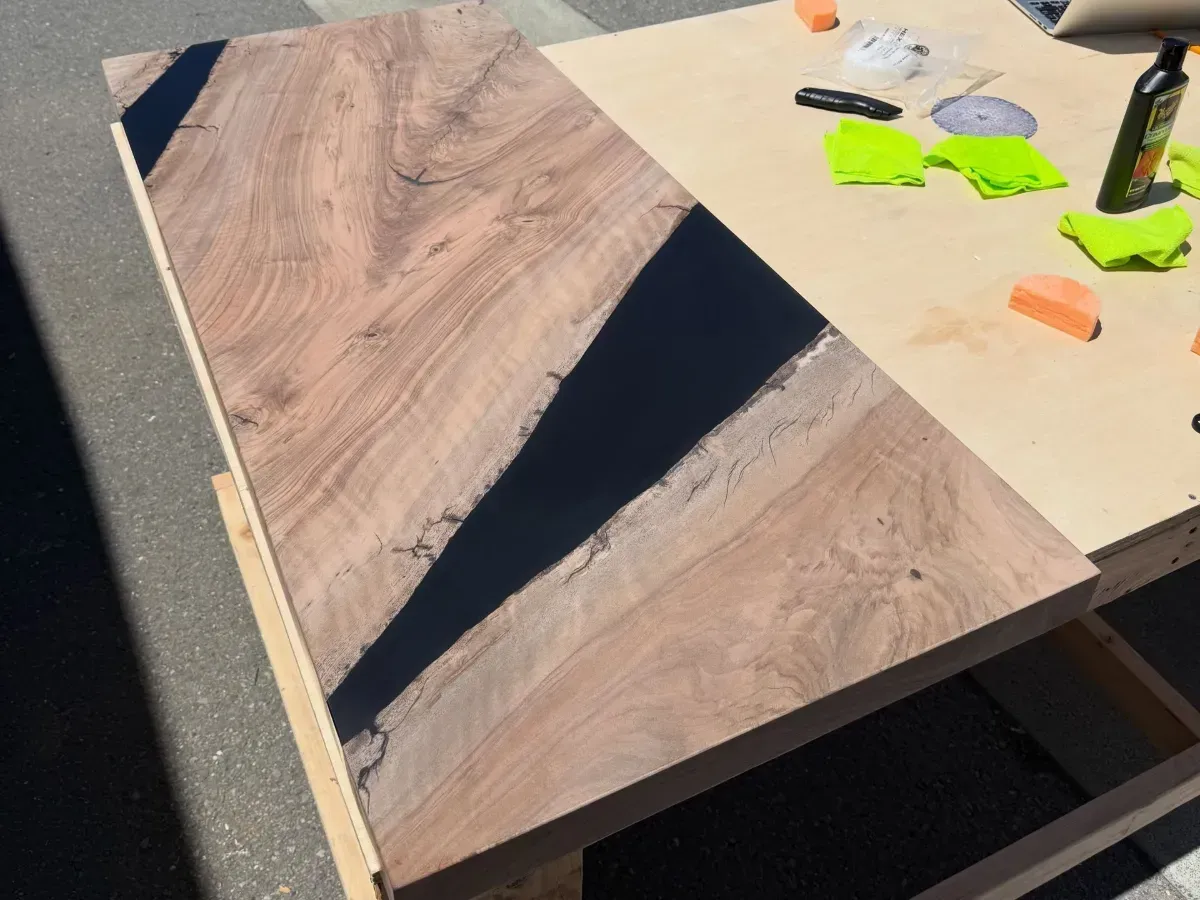 Wooden tabletop with dark triangular inlays, partly assembled on a workbench with tools nearby