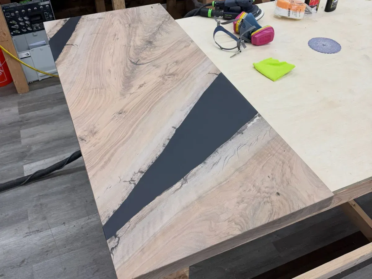 Wood-patterned tabletop with a dark gray diagonal inlay on a workbench, with tools nearby