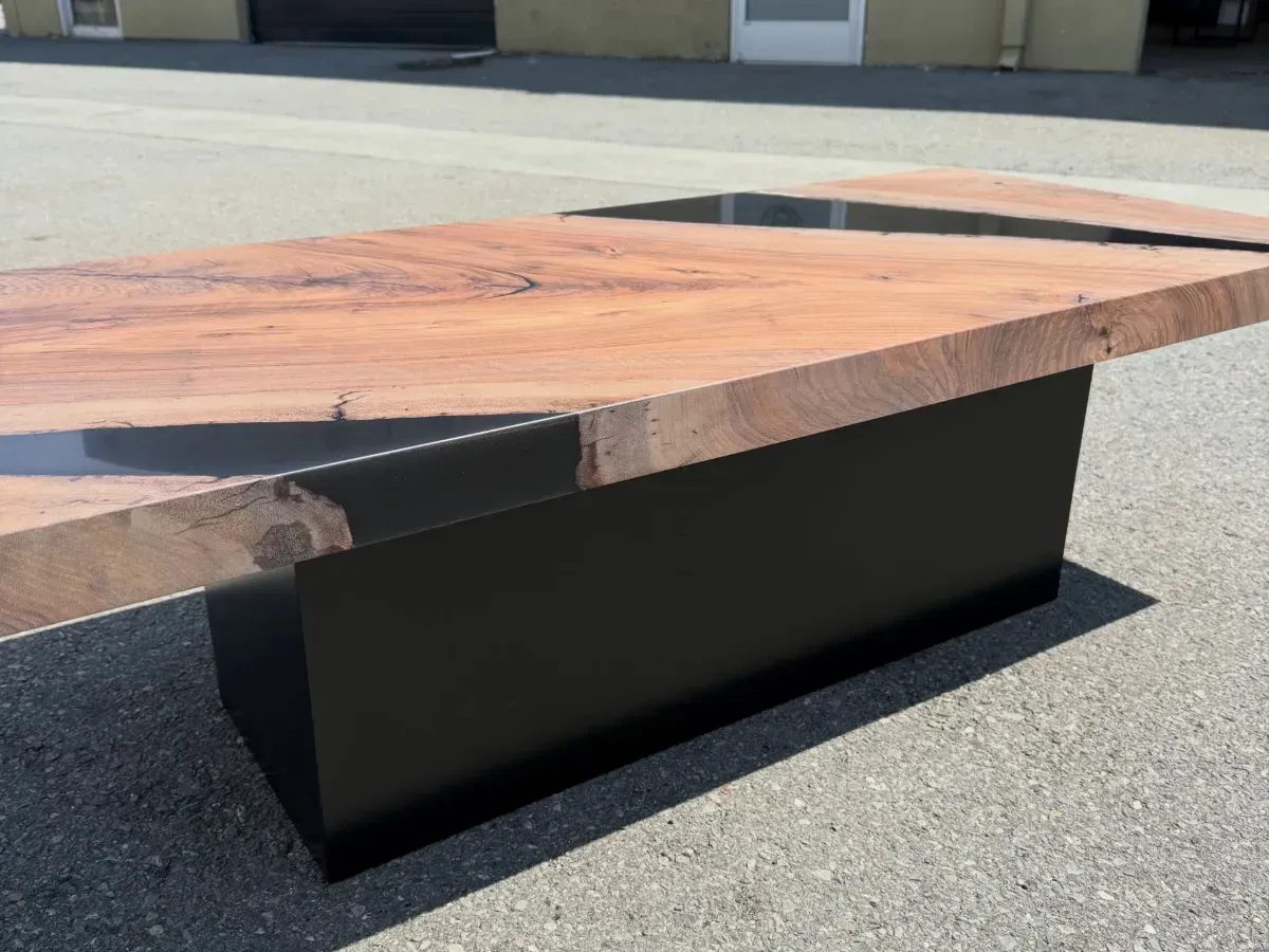 Rectangular outdoor picnic table with a wooden top and black metal base on pavement