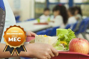 Pessoa segurando bandeja com almoço escolar: salada, fruta, wrap. Crianças ao fundo. Selo