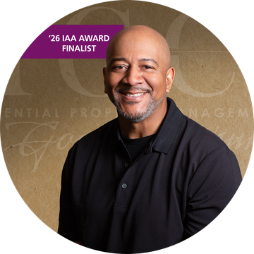Smiling bald man wearing a black shirt, set against a brown background with text.