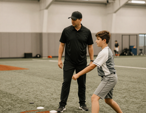 Coach demonstrating pitching mechanics to a young player