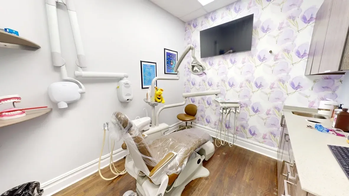 A dental office with a dental chair and a television on the wall.