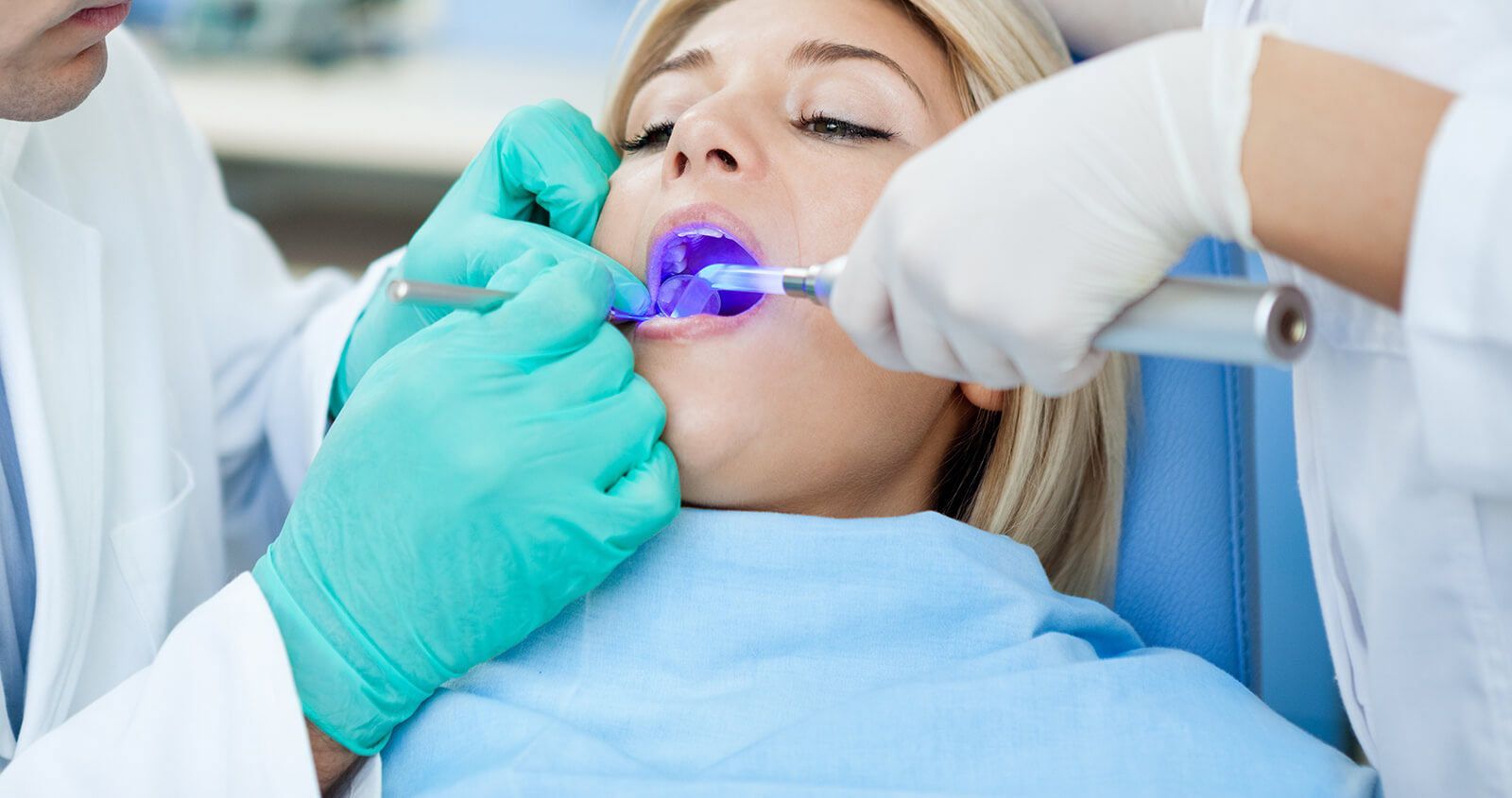 A woman is getting her teeth examined by a dentist.