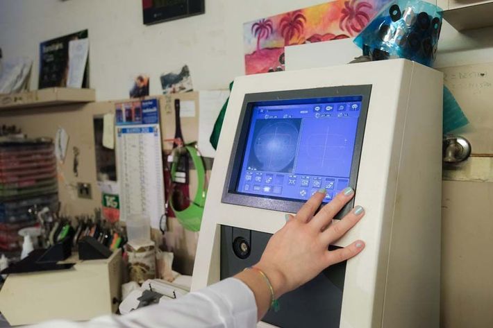 Persona che utilizza un dispositivo touchscreen in un'officina o un laboratorio disordinato.