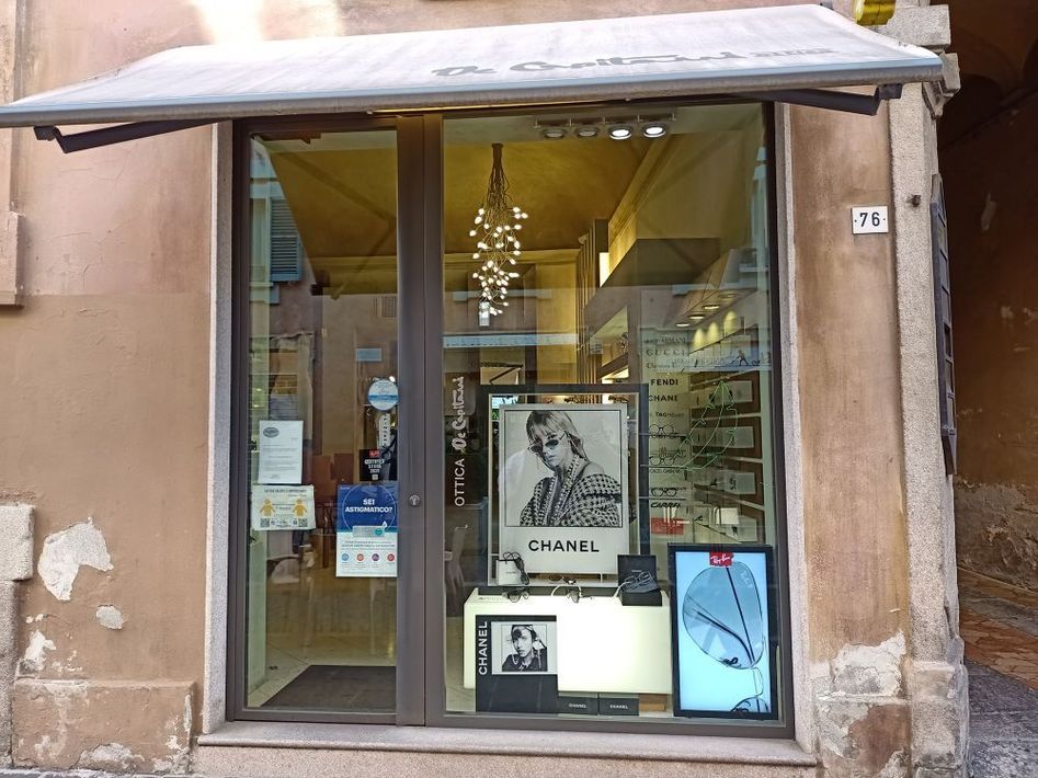 Vetrina con poster artistici incorniciati sotto una tenda da sole grigia