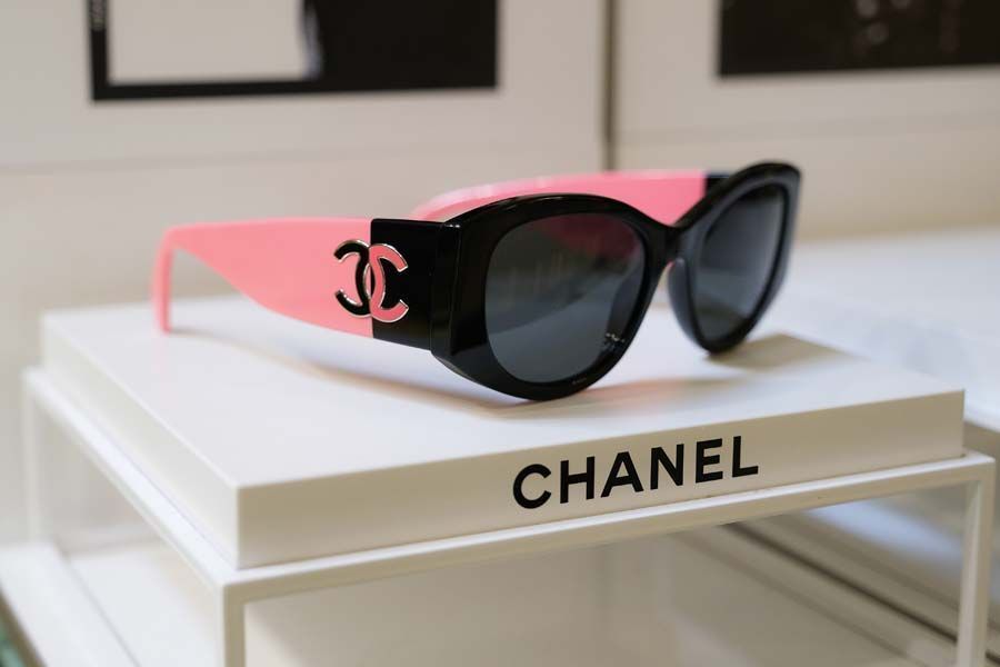 Occhiali da sole Chanel neri con aste rosa su una scatola Chanel bianca