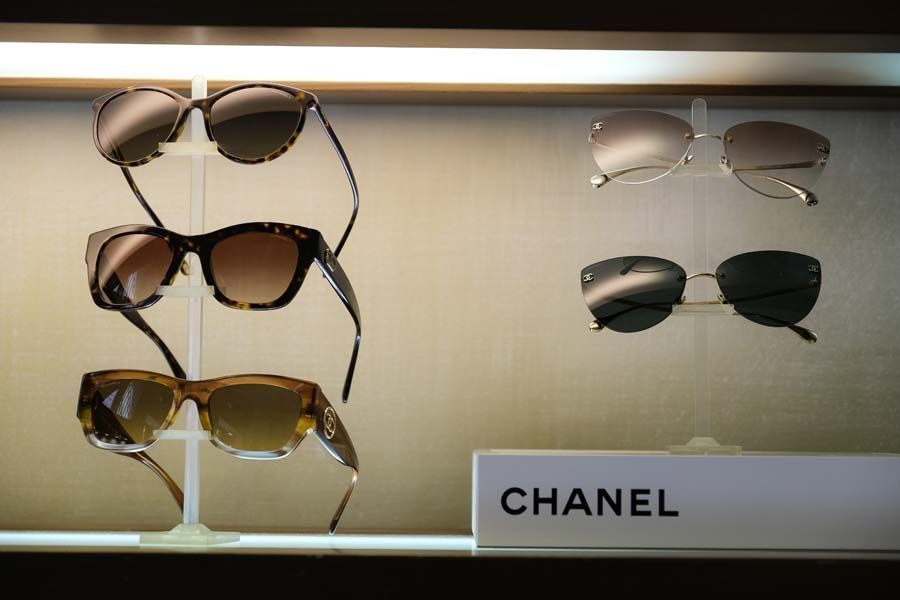 Esposizione di occhiali da sole Chanel in vari colori su uno scaffale di un negozio.