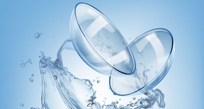 Lenti a contatto trasparenti che schizzano nell'acqua su uno sfondo azzurro chiaro