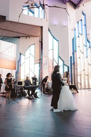 Bride and groom dancing at wedding reception. Smoke, band members, and stage lights in background.