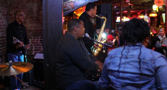 Band performing on a stage with a microphone and keyboard in a dimly lit bar.