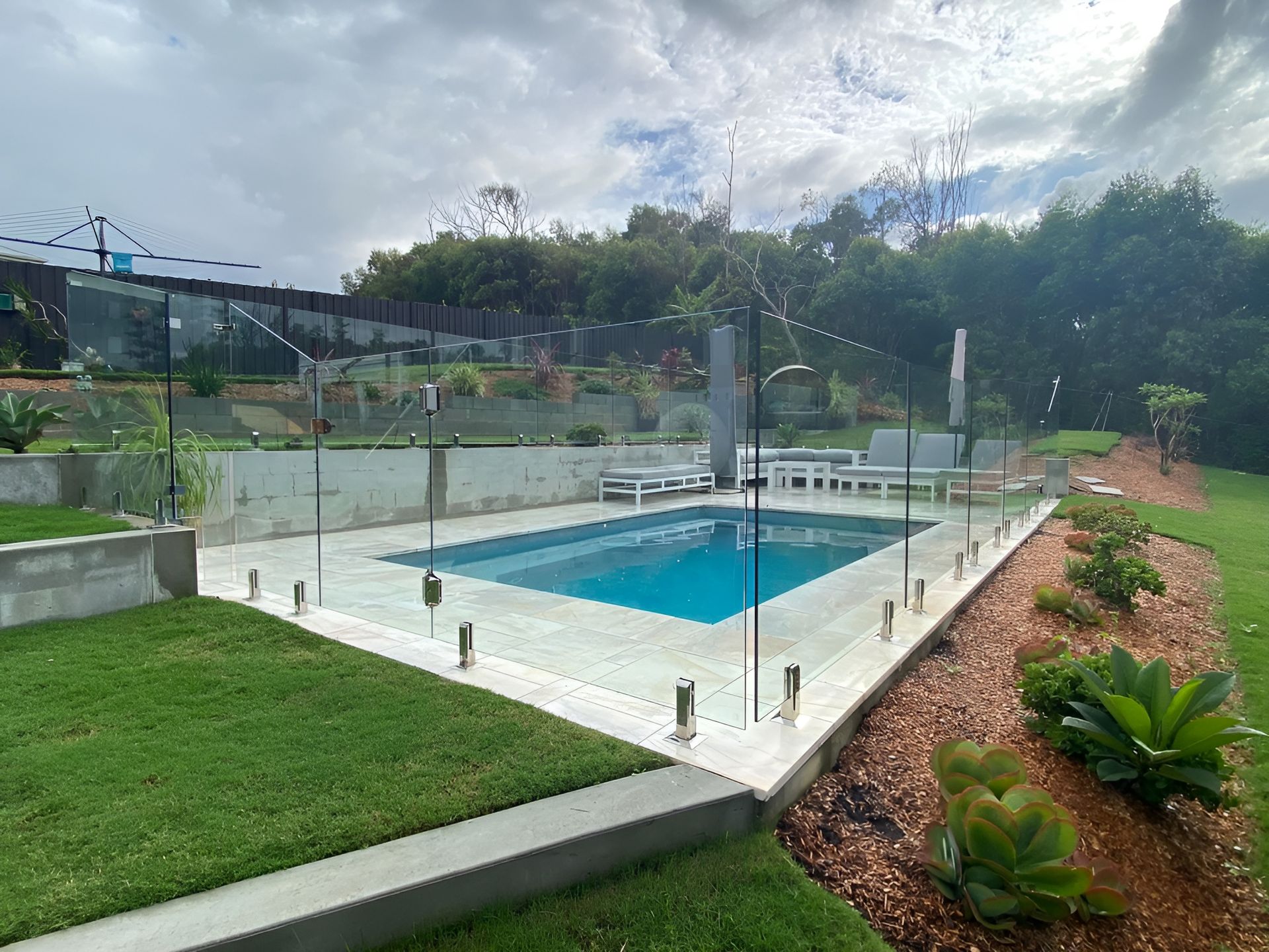 Swimming Pool Surrounded by Glass Fencing — Master Glass & Glazing in Belmont, NSW