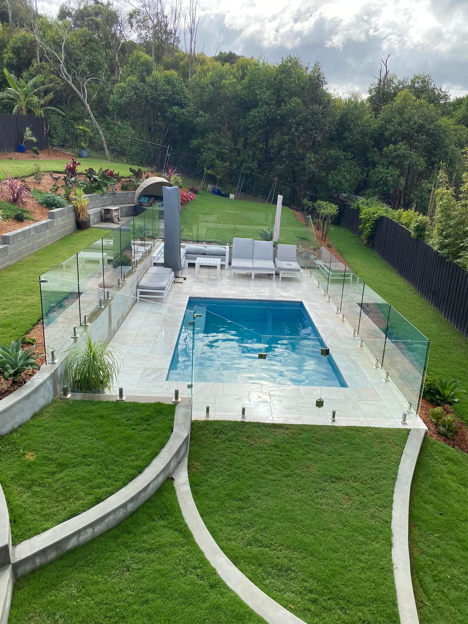A Rectangular Swimming Pool Surrounded by A Patio and Glass Fencing — Master Glass & Glazing in Newcastle, NSW