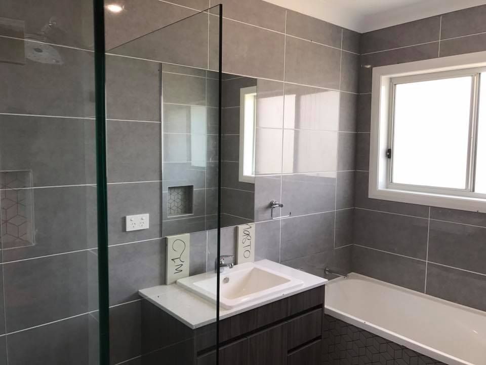 A Glass Shower Door Is in The Foreground — Master Glass & Glazing in Charlestown, NSW