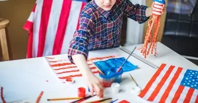 Child painting a table with red, white, and blue stripes and stars for a patriotic craft project