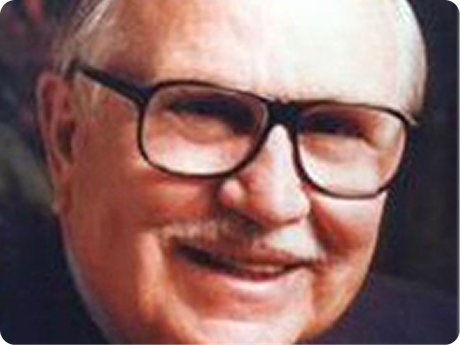 Close-up portrait of a smiling man with glasses and a mustache