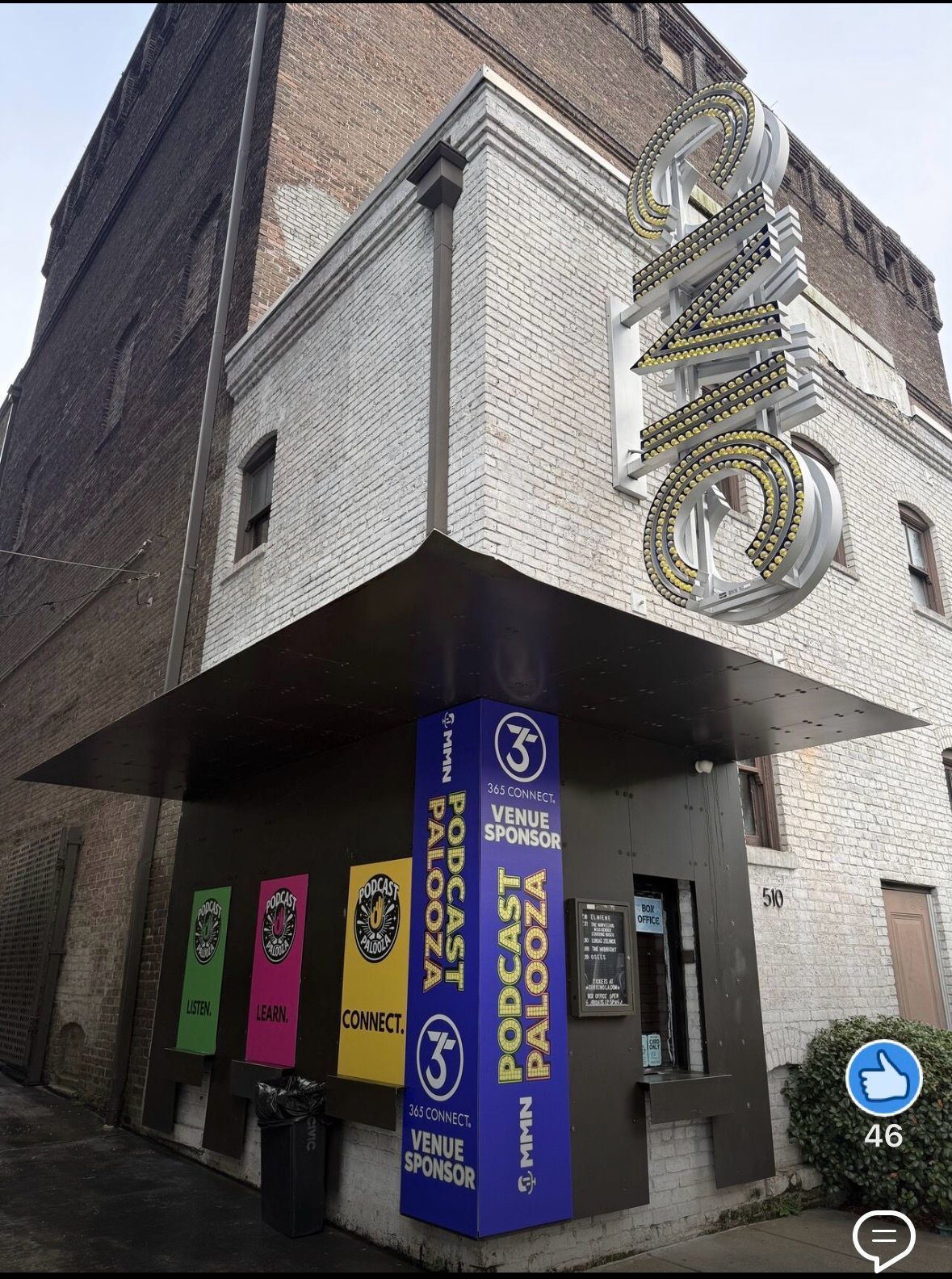 Corner storefront with purple signage and a large hanging sign on a brick building.