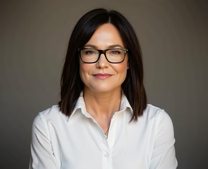 Woman wearing glasses and a white shirt, smiling, headshot.