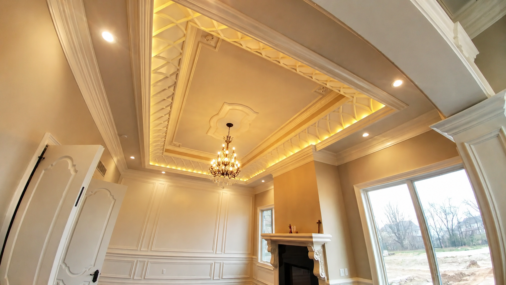 Elegant empty living room with tray ceiling, chandelier, fireplace, and large window overlooking outdoors
