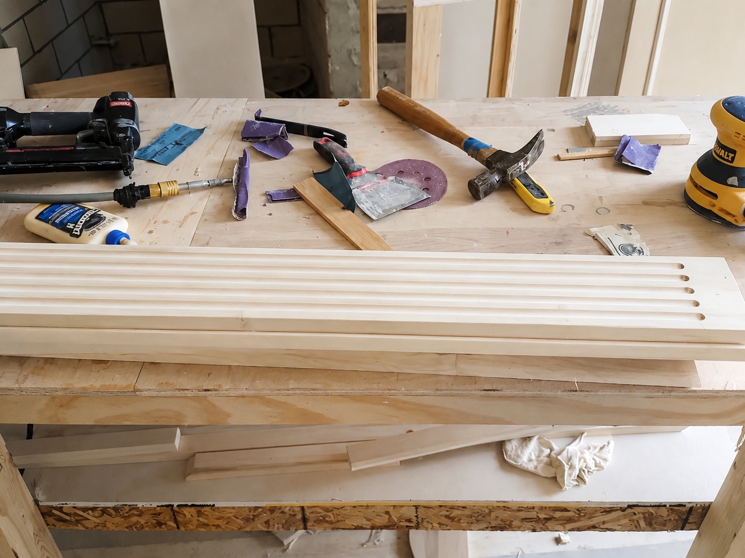 Wooden workbench with hand tools and lumber pieces in a workshop
