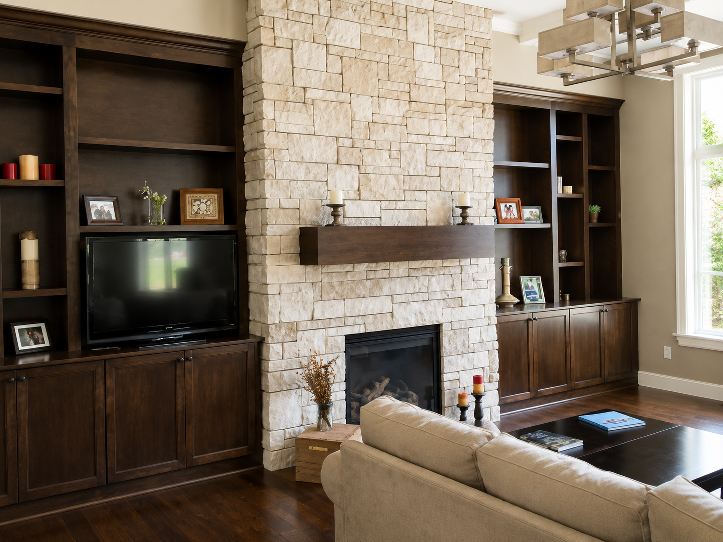 Living room with stone fireplace, dark wood built-ins, TV, and beige sofa