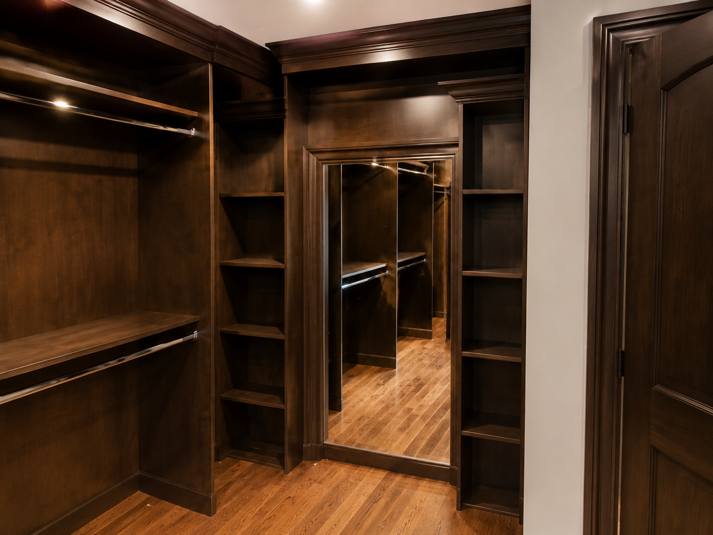 Empty dark-wood walk-in closet with mirrored doors and built-in shelves