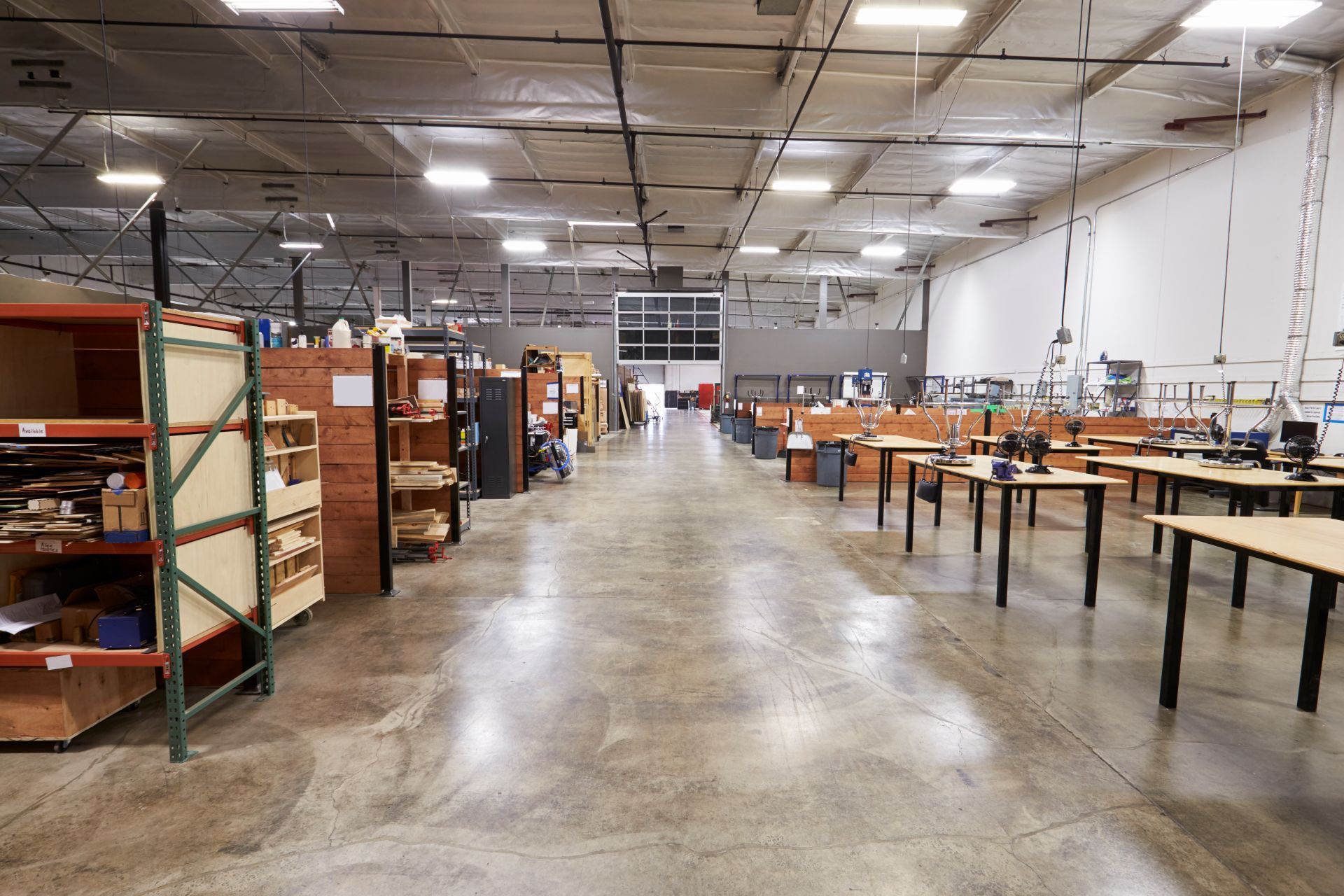 Large warehouse interior with work tables, shelving, and concrete floor.