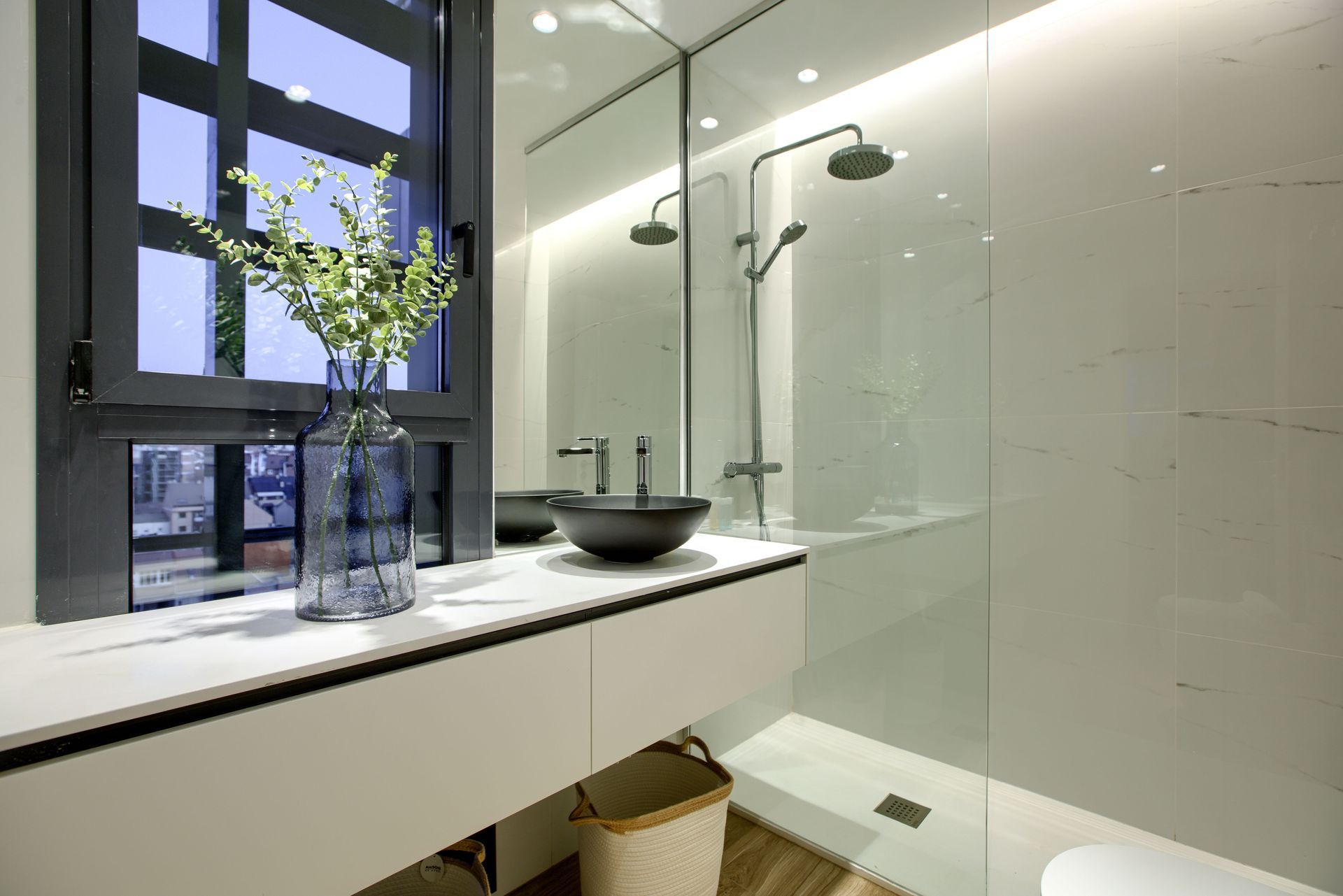Frameless glass panel in a modern white bathroom showcasing custom shower screens.