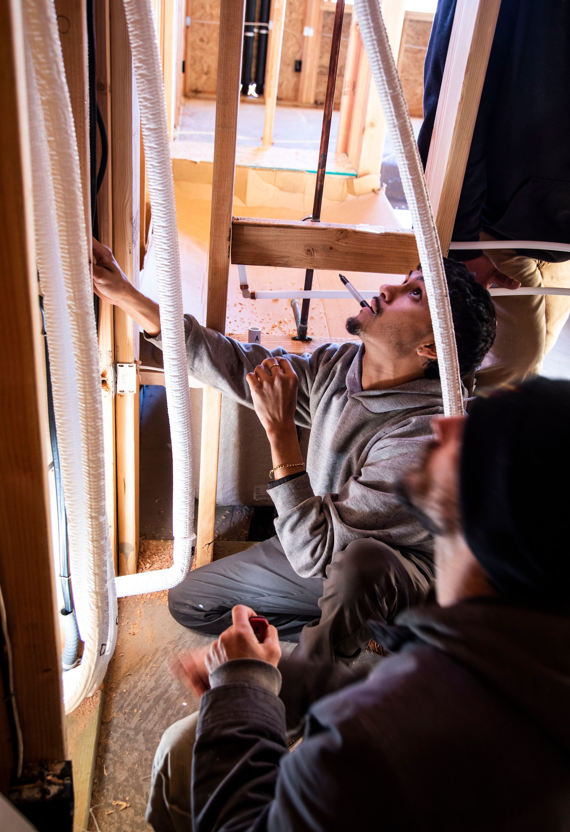 Two Thompson Heating and Cooling technicians are working on a ladder in a building under construction.