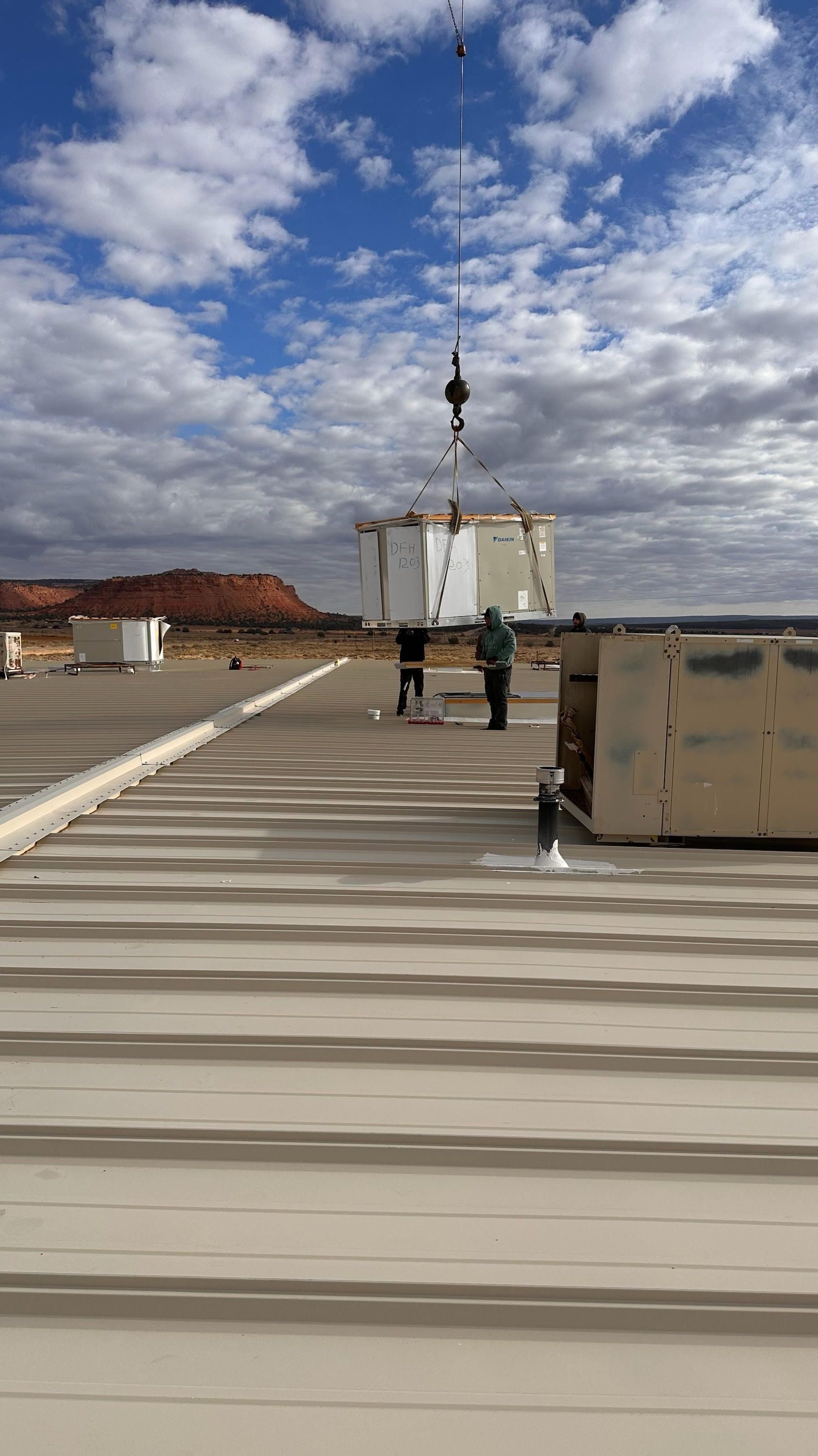 A crane is lifting a box on top of a roof.