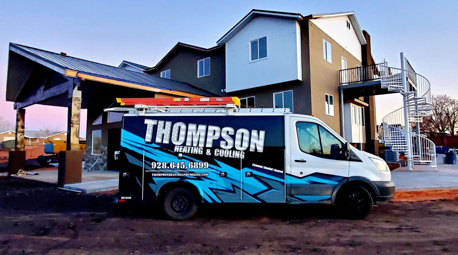A thompson van is parked in front of a building under construction.