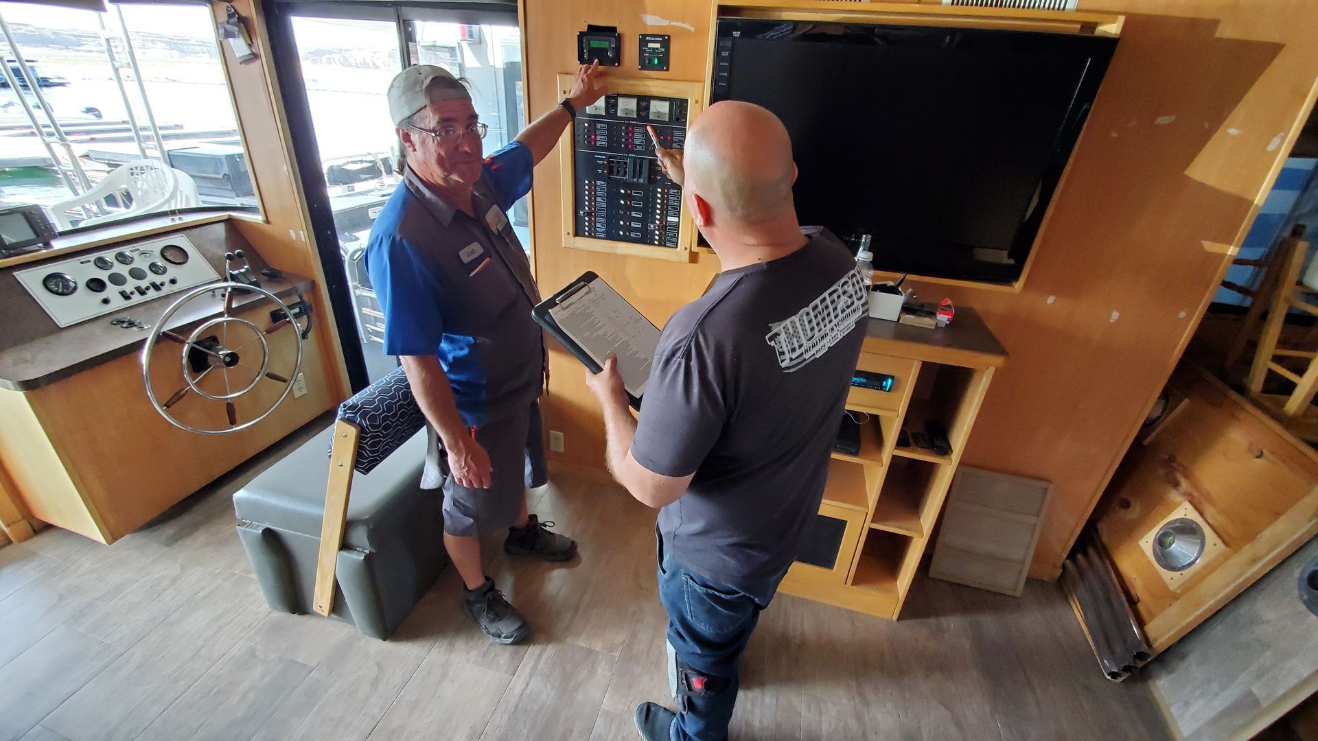 Two men are standing in a room on a boat talking to each other.