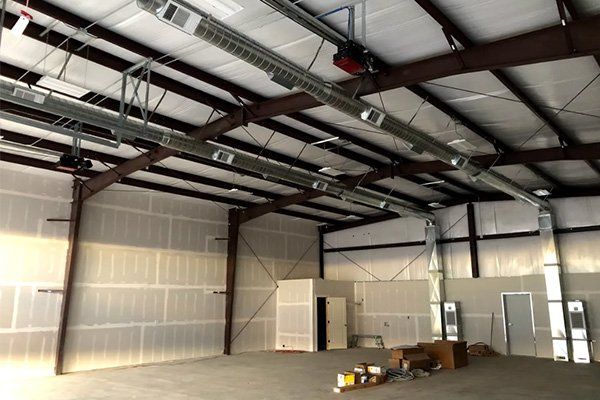 A large empty building with a lot of ducts hanging from the ceiling