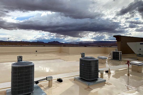 There are a lot of air conditioners on the roof of a building.