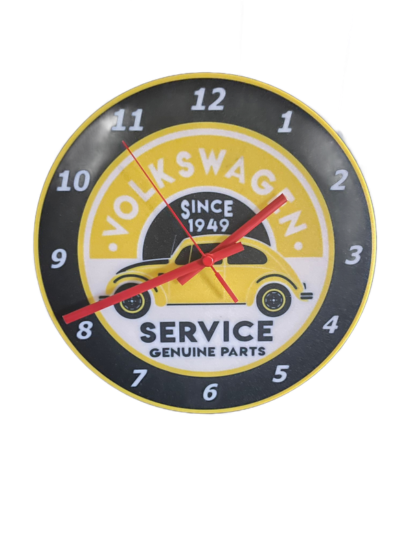 Vintage Volkswagen serviceklok met geel autologo en rode wijzers op een donkere wijzerplaat.