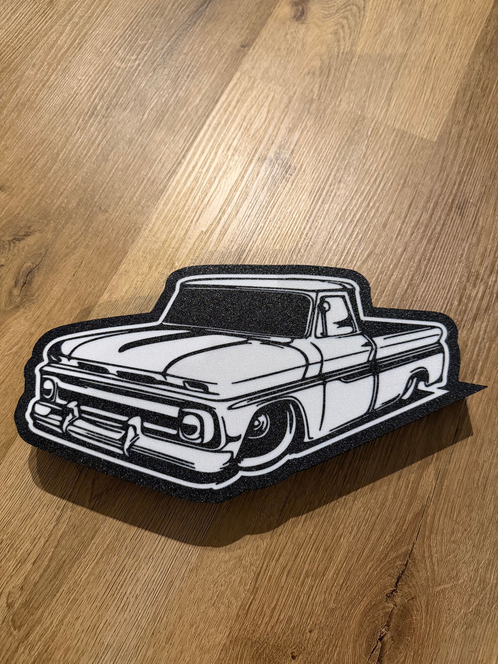 Zwart-wit geborduurd klassiek cabriolet-embleem op een beige stoffen achtergrond.