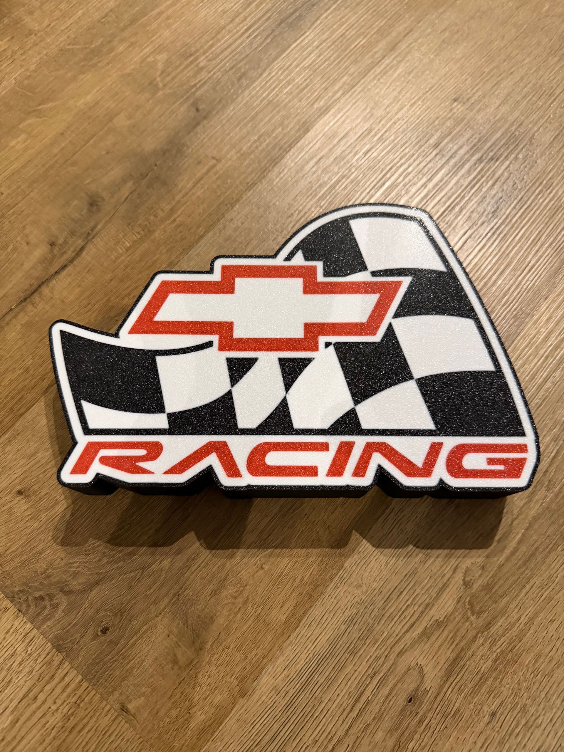 Chevrolet Racing sticker met zwart-wit geblokt vlagontwerp op een houten ondergrond