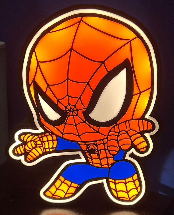 Chibi Spider-Man in een rood-blauw pak, gehurkt met webpatronen en grote witte ogen op een donkere achtergrond.