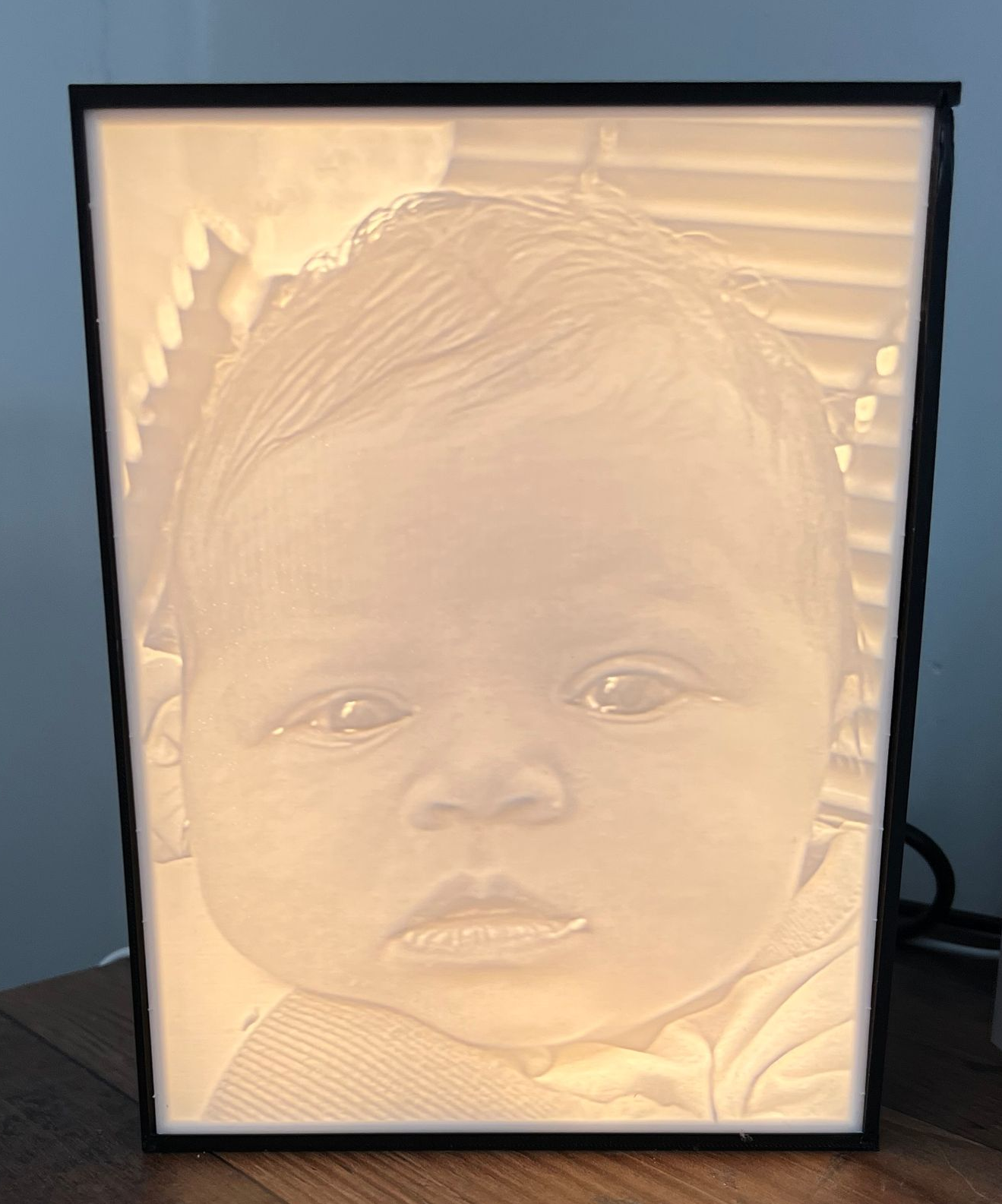 Ingelijst, verlicht portret van een baby met een zachte beige gloed.