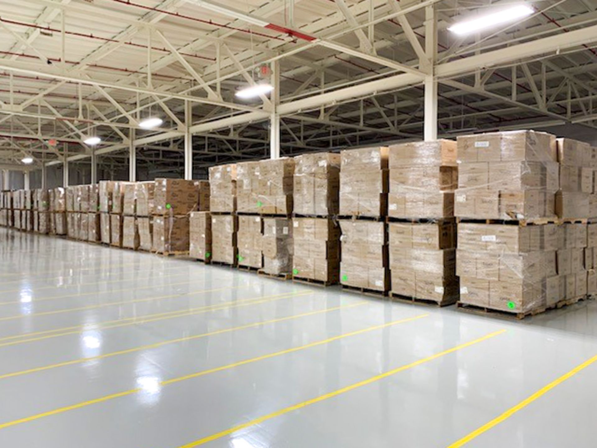 Warehouse aisle with stacked cardboard boxes on pallets along a polished floor