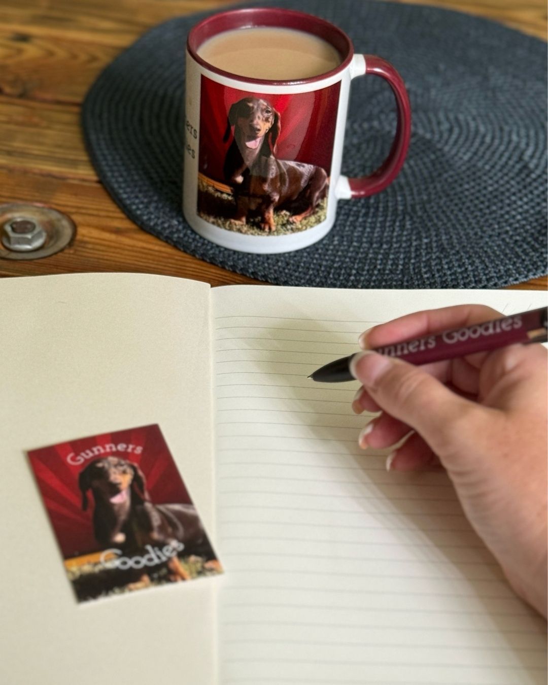 Gunners Goodies notebook, branded mug and pen beside a business card
