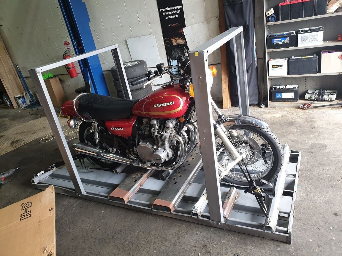 A Red Motorcycle Is Sitting On Top Of A Metal Crate In A Garage — Motorcycle Transporters In Manunda, QLD