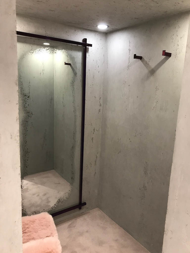 detail of a dressing room interior with white beton stucco plaster walls and a mirror