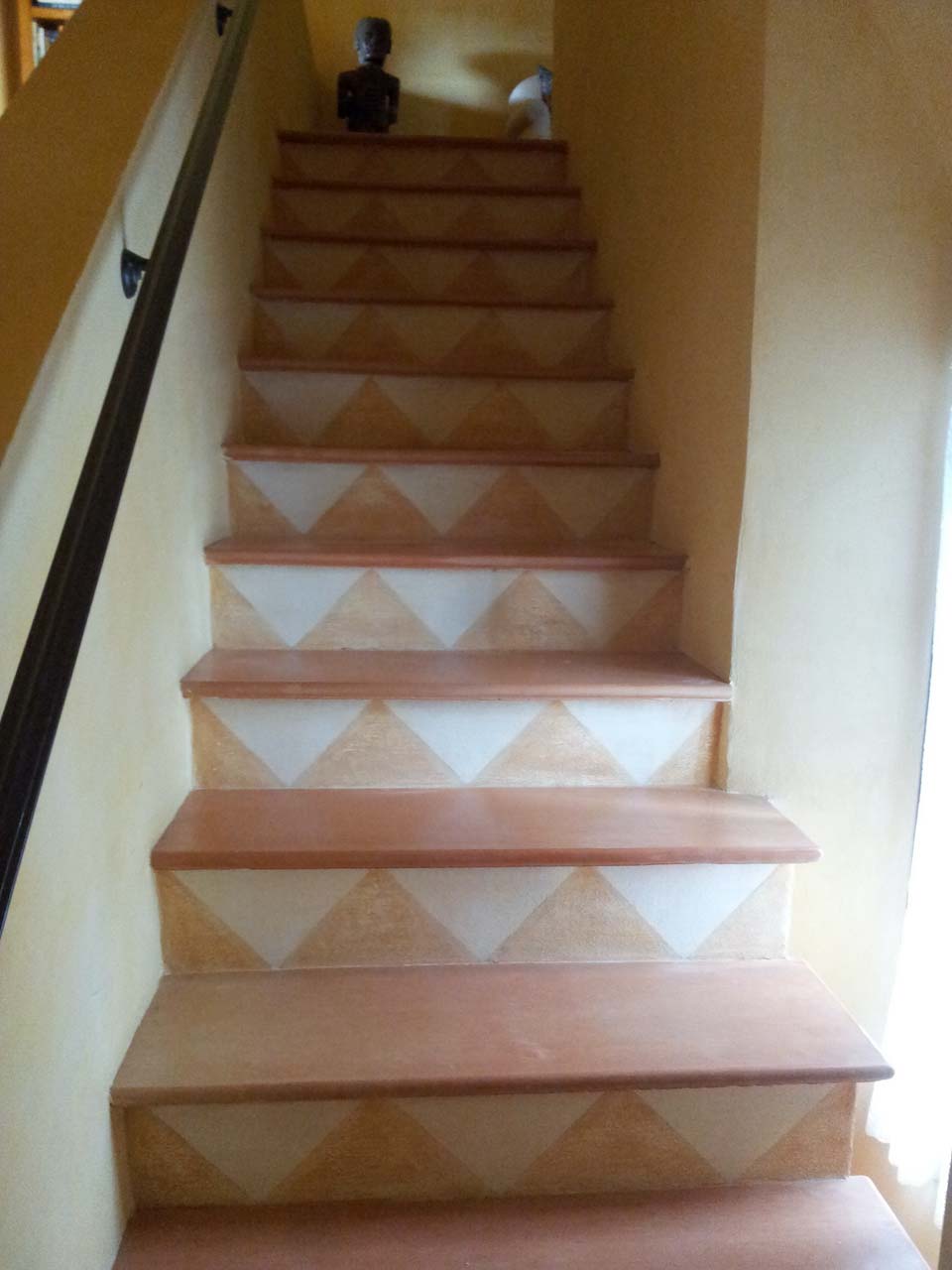 picture of an internal stair decorated with white and orange triangles made by venezia stucco lime paint product for an ancient effect